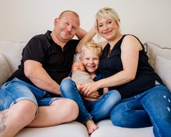 Vater Mutter großer Bruder und neugeborenes Baby kuscheln auf dem Sofa